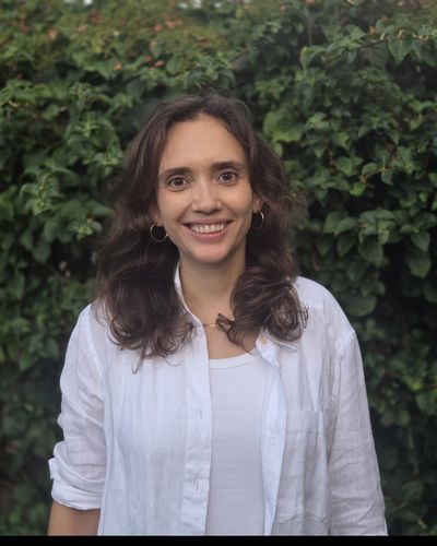 Mandy van Zwam, smiling, standing in front of a green hedge